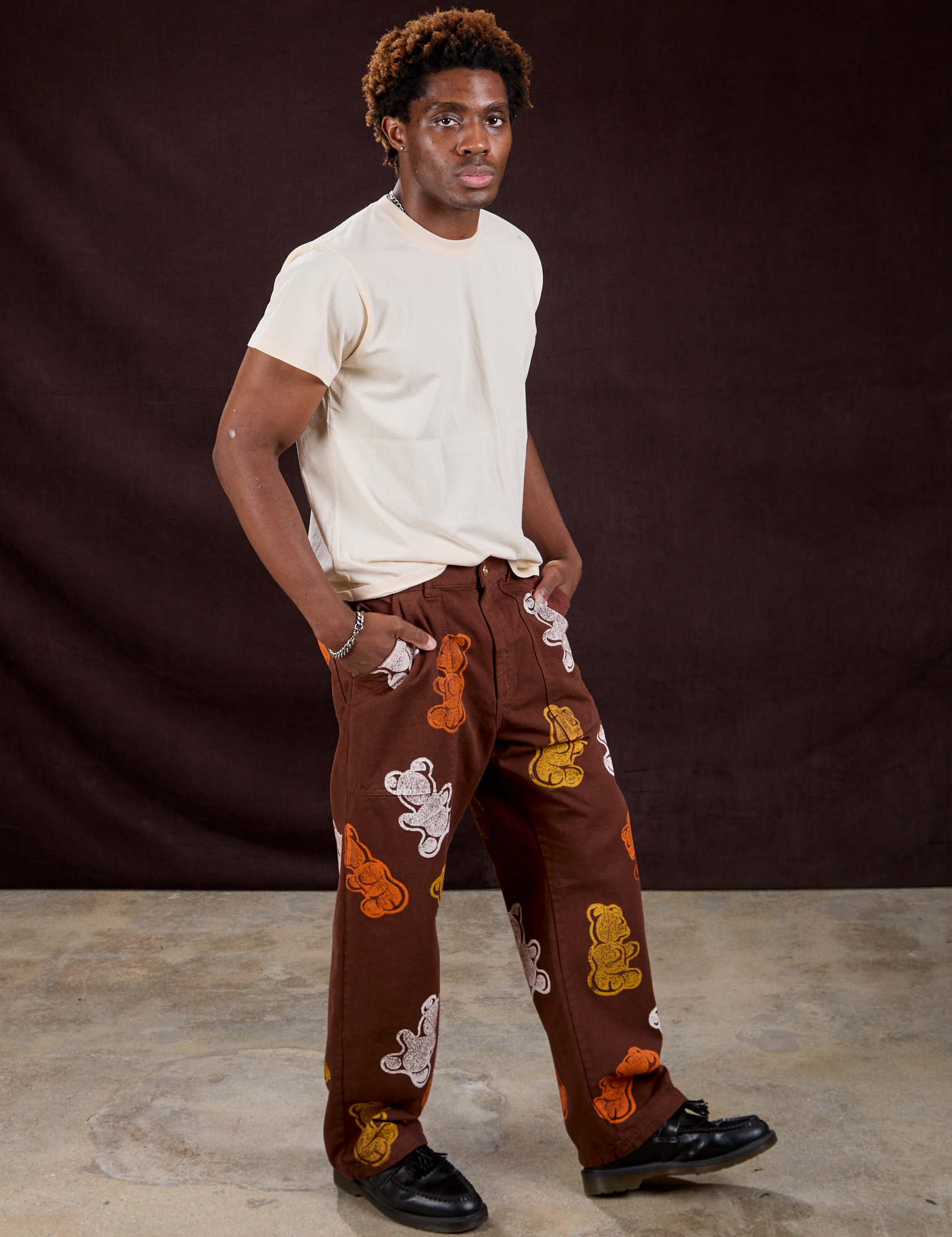 Angled front view of Gummy Bear Paintstamped Work Pants in Fudgesicle Brown and Organic Vintage Tee in Vintage Off-White