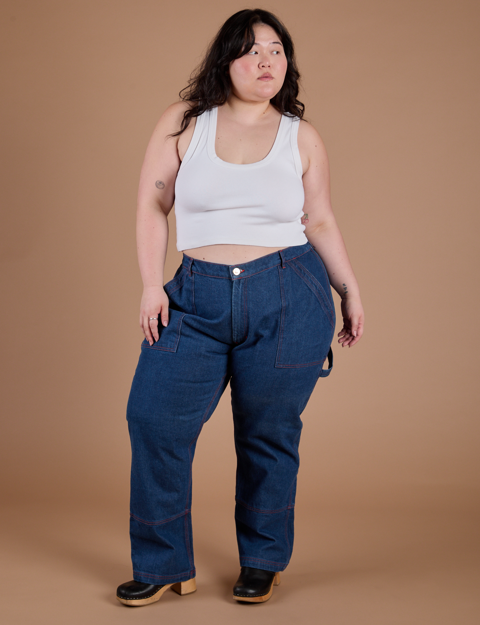 Ashley is 5’7” and wearing 1XL Carpenter Jeans in Dark Wash paired with a Cropped Tank in Vintage Tee White