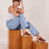 Tiara is sitting on a wooden box wearing Carpenter Jeans in Light Wash