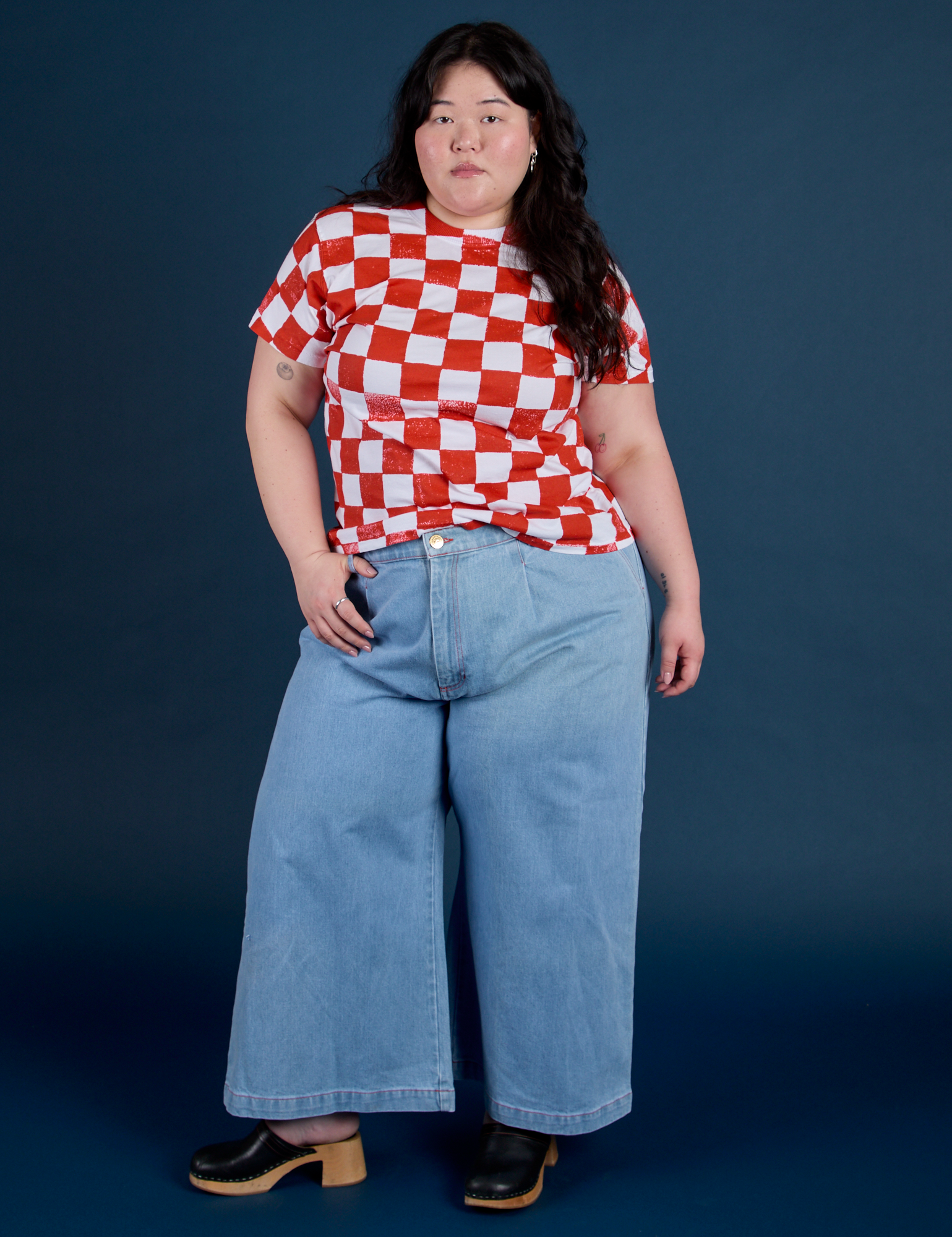 Ashley is wearing Checker Organic Tee in Red and light wash Indigo Wide Leg Trousers
