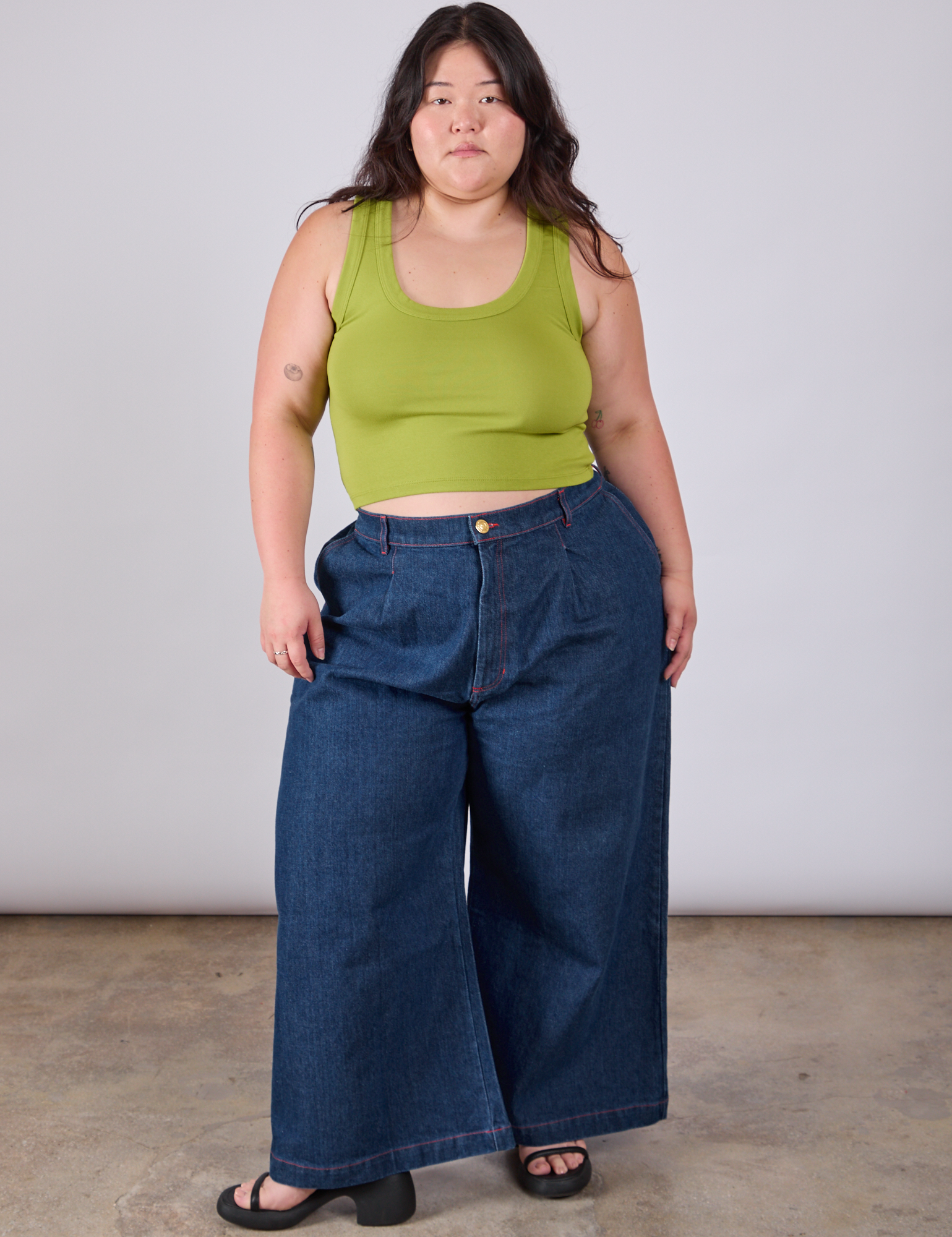 Ashley is wearing Cropped Tank Top in Gross Green paired with dark wash Indigo Wide Leg Trousers