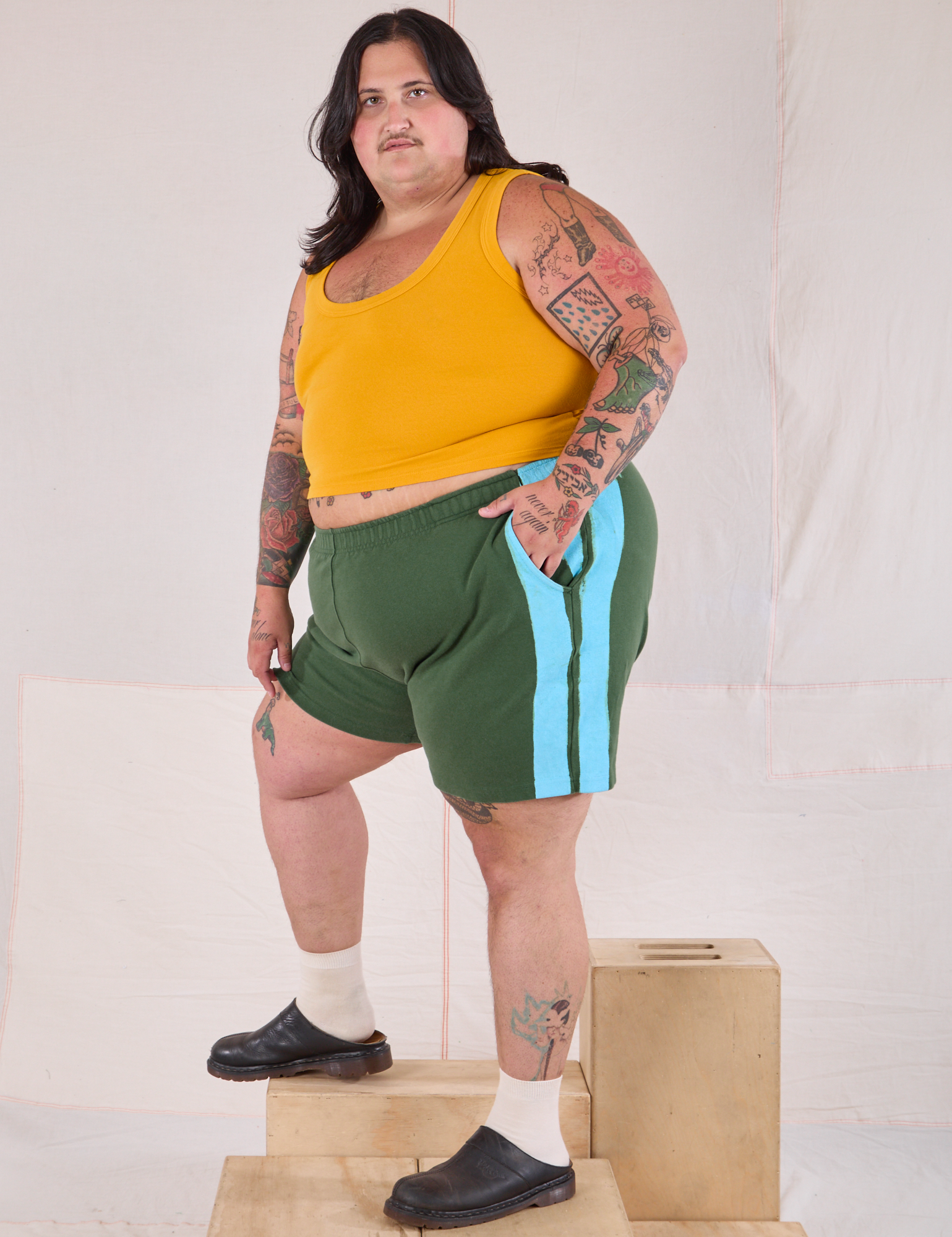 Angled view of Painted Stripe Easy Shorts in Dark Emerald Green and golden yellow Cropped Tank on Sam