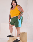 Angled view of Painted Stripe Easy Shorts in Dark Emerald Green and golden yellow Cropped Tank on Sam