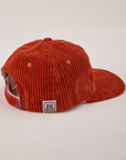 Side view of Dugout Corduroy Hat in Paprika. Big Bud label sewn on edge of hat.