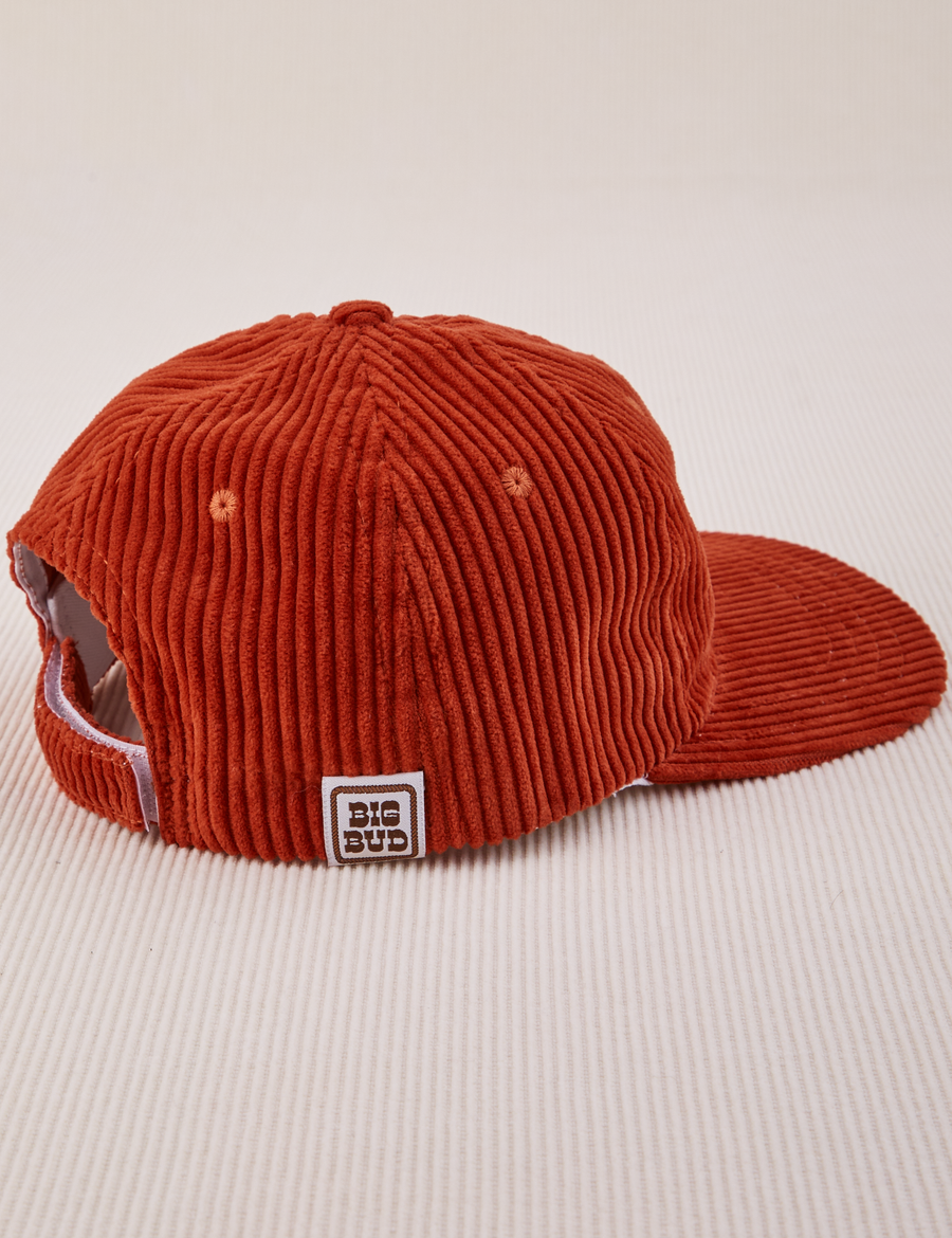 Side view of Dugout Corduroy Hat in Paprika. Big Bud label sewn on edge of hat.