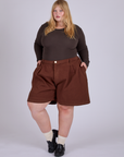 Juliet is wearing Pleated Trouser Shorts in Fudgesicle Brown and espresso brown Long Sleeve Baby Tee
