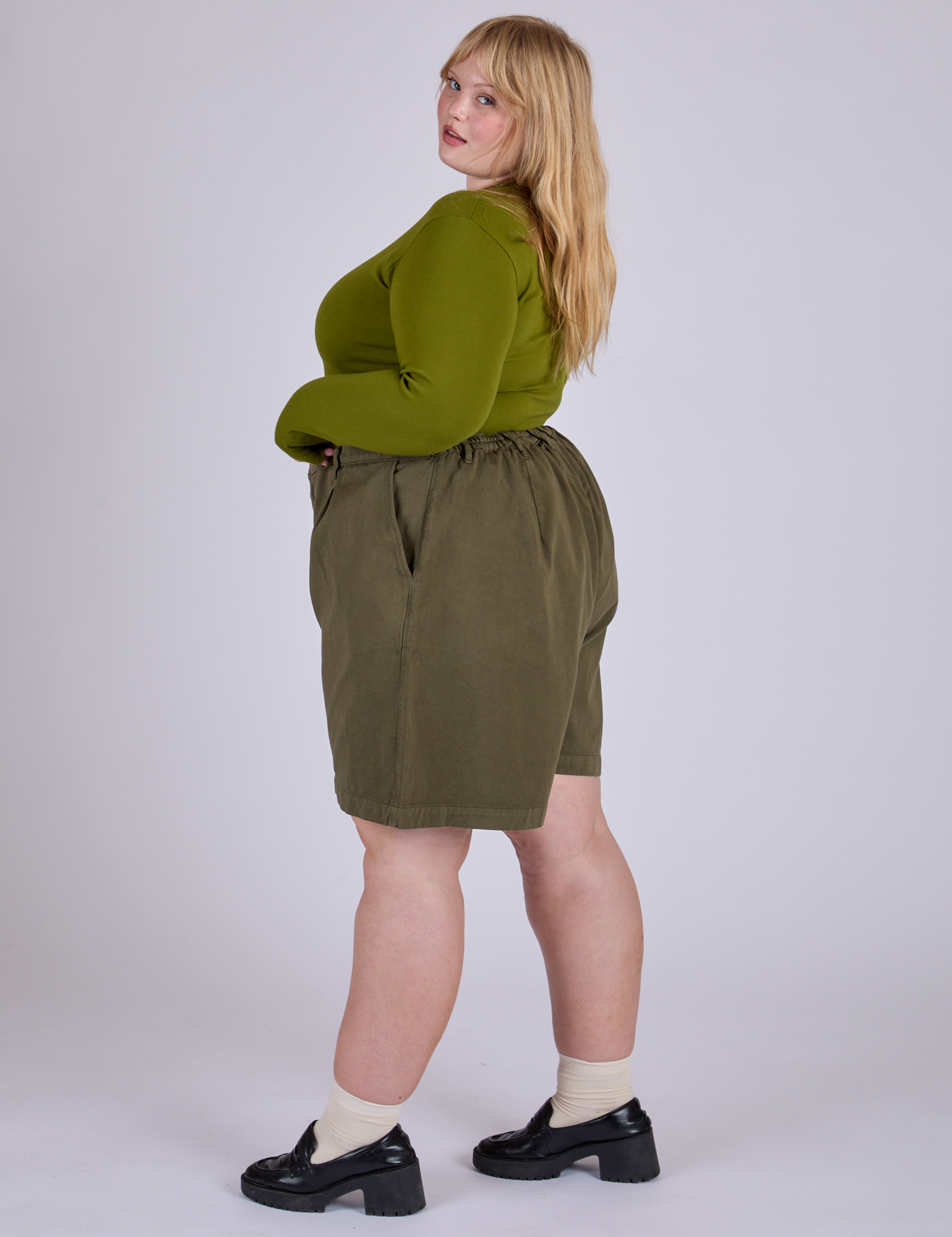 Side view of Pleated Trouser Shorts in Surplus Green and summer olive Long Sleeve Baby Tee