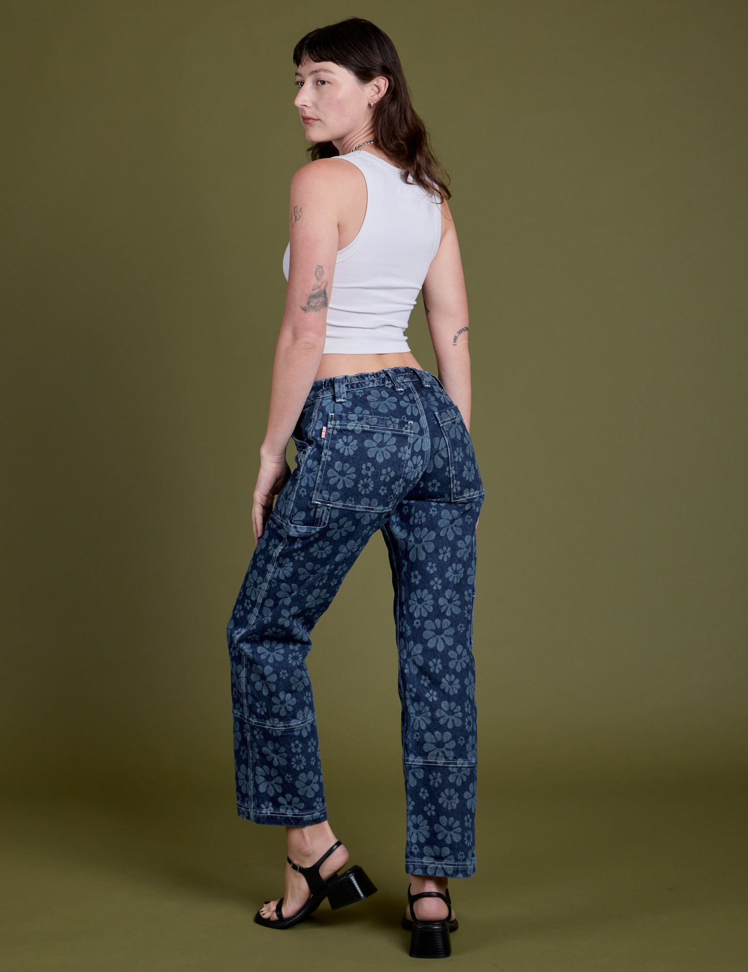 Angled back view of Lazy Daisy Mid-Rise Carpenter Jeans and vintage tee white Cropped Tank on Alex