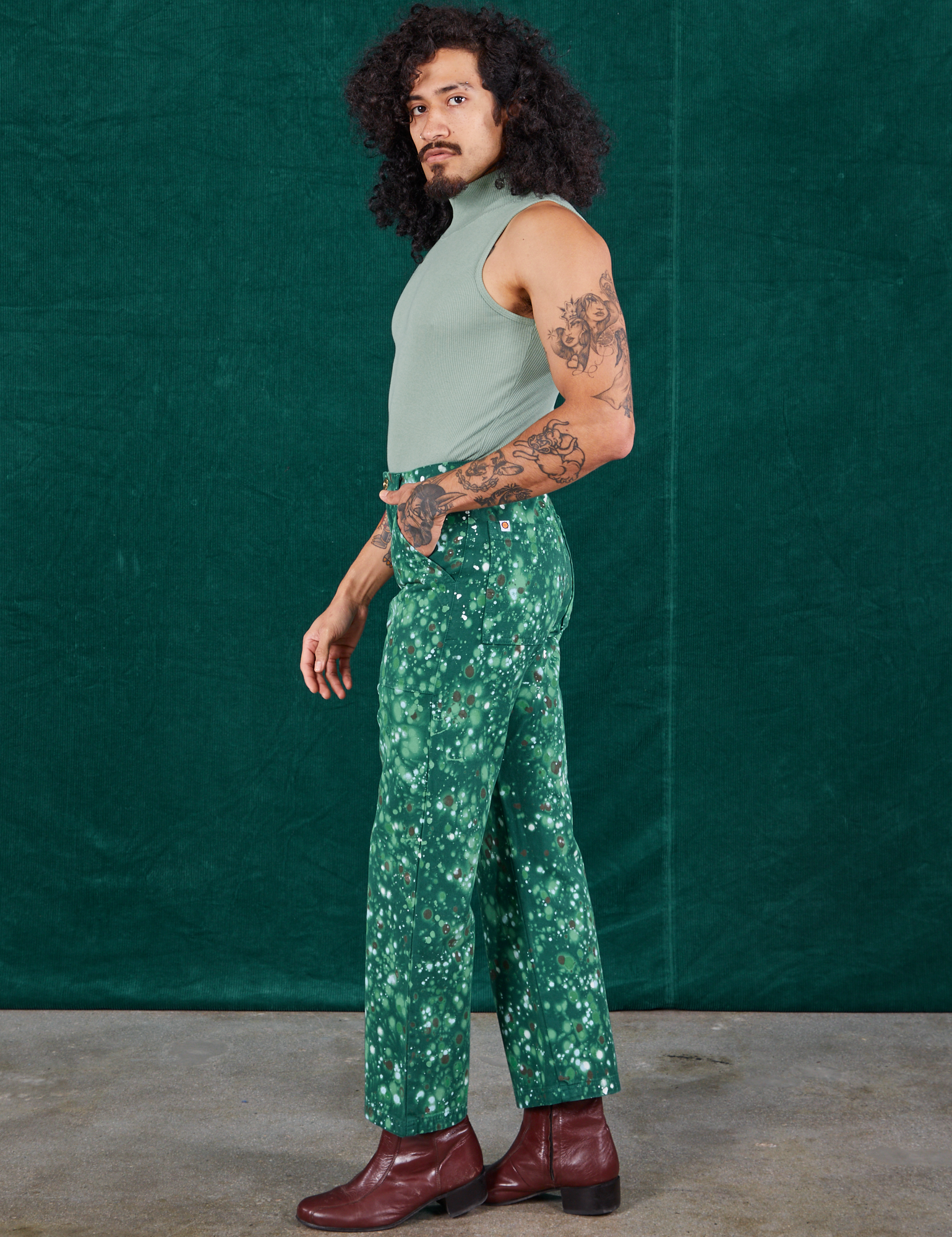 Side view of Marble Splatter Work Pants in Hunter Green and sage green Sleeveless Turtleneck on Jesse