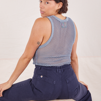 Tiara is sitting on a wooden crate with her back turned. She is wearing Mesh Tank Top in Periwinkle and navy Western Pants