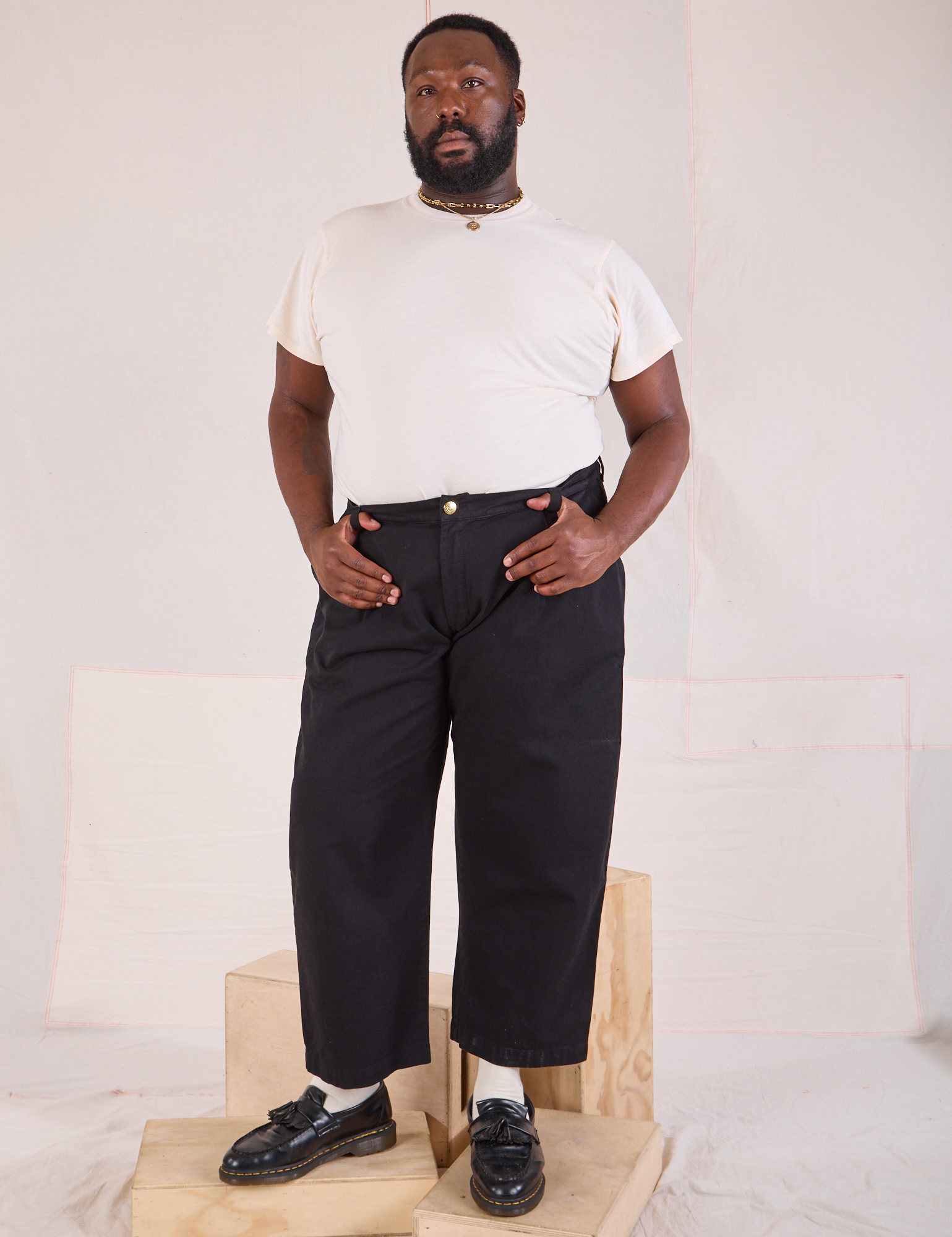 Elijah is 6&#39;3&quot; and wearing 1XL Mid-Rise Pleated Trousers in Basic Black paired with Organic Vintage Tee in vintage tee off-white