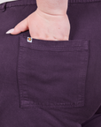 Back pocket close up of Work Pants in Nebula Purple. Catie has her hand in the pocket.