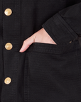 Field Coat in Basic Black front pocket close up. Alex has her hand in the pocket.