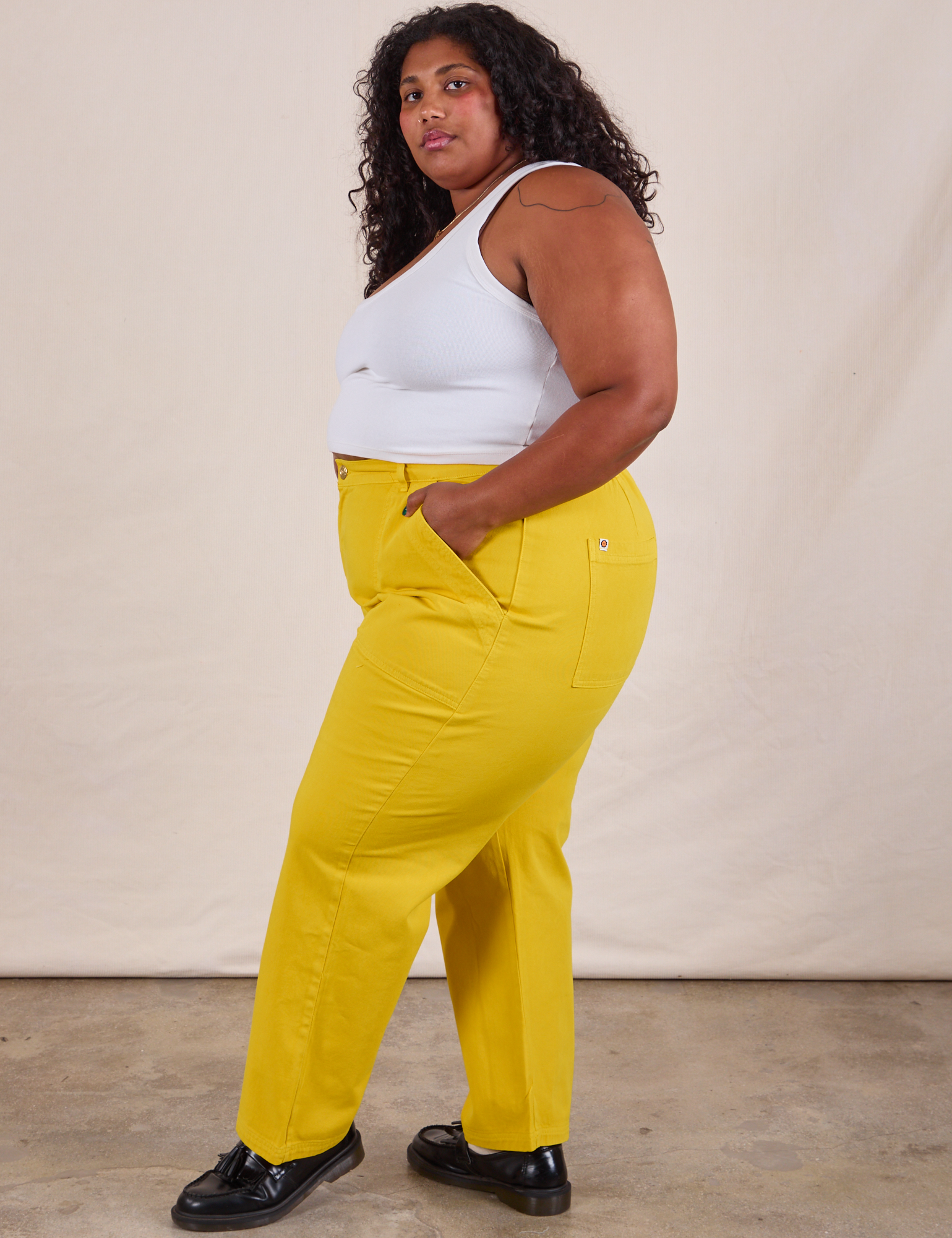 Side view of Work Pants in Golden Yellow and Cropped Tank in Vintage Tee Off-White on Morgan