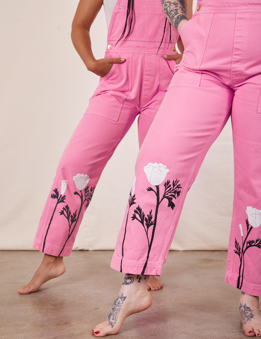 Gabi and Sydney are both wearing California Poppy Overalls in Bubblegum Pink. Both have their left legs kicked out a little and their hands in the pant pocket.