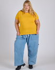 Juliet is 5’7” and wearing L Jr. Varsity Tee in Sunshine Yellow paired with light wash Denim Drop Pocket Pants