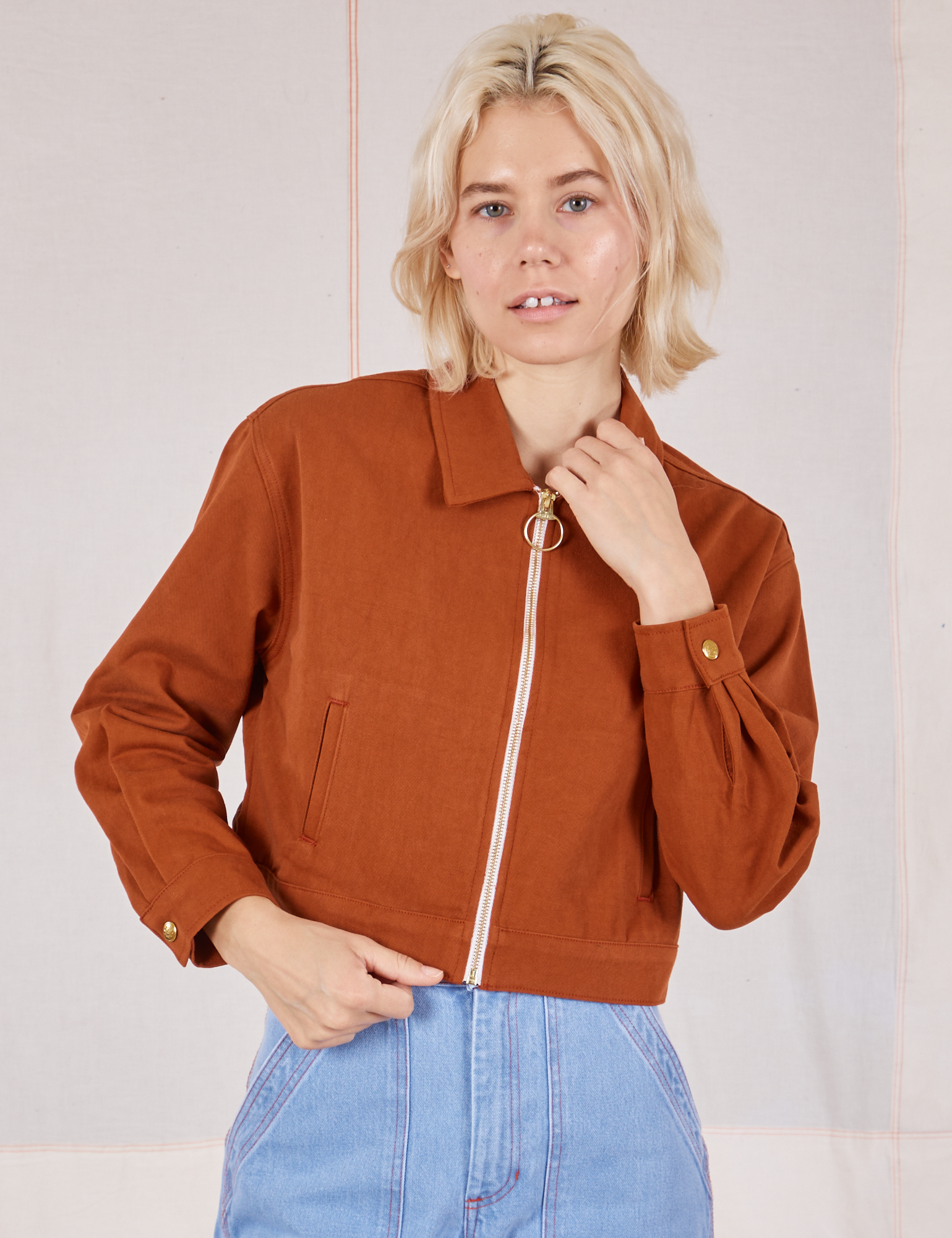 Madeline is wearing a zipped up Ricky Jacket in Burnt Terracotta