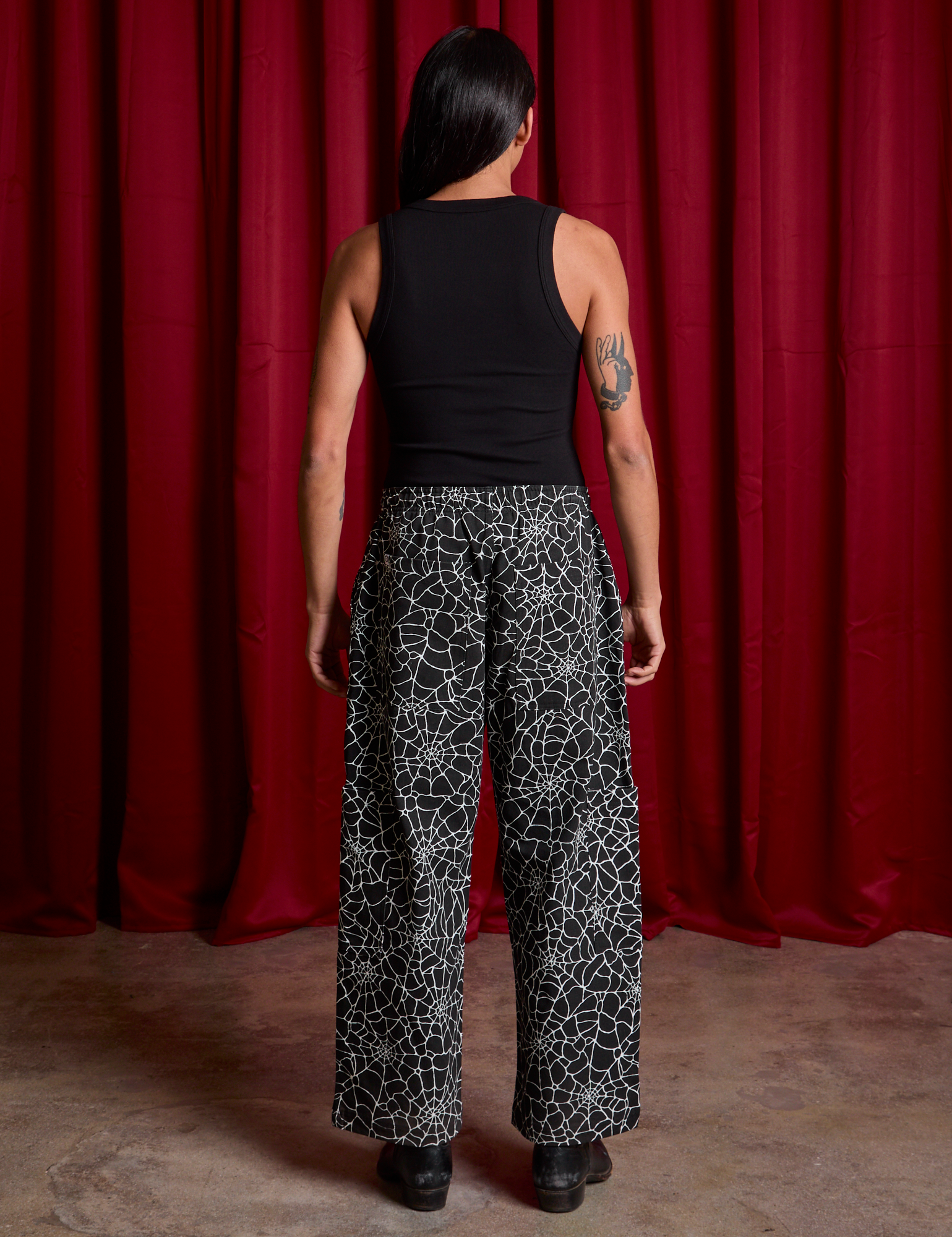 Back view of Drop Pocket Cargo Pants in Spider Webs and black Cropped Tank on Anthony