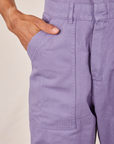 Front pocket close up of Short Sleeve Jumpsuit in Faded Grape. Jesse has their hand in the pocket.