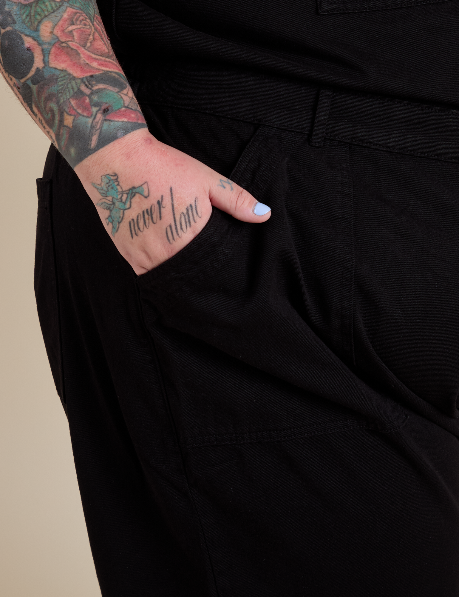 Close up of Sam's hand in the front pocket of Short Sleeve Jumpsuit in Basic Black