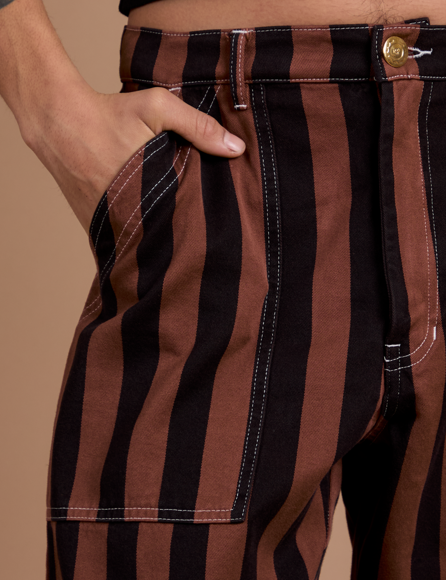 Close up of Anthony's hand in the front pocket of Black Stripe Work Pants in Fudgesicle Brown