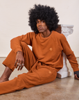 Jerrod is wearing Cropped Rolled Cuff Sweatpants in Burnt Terracotta and matching Heavyweight Crew Sweatshirt