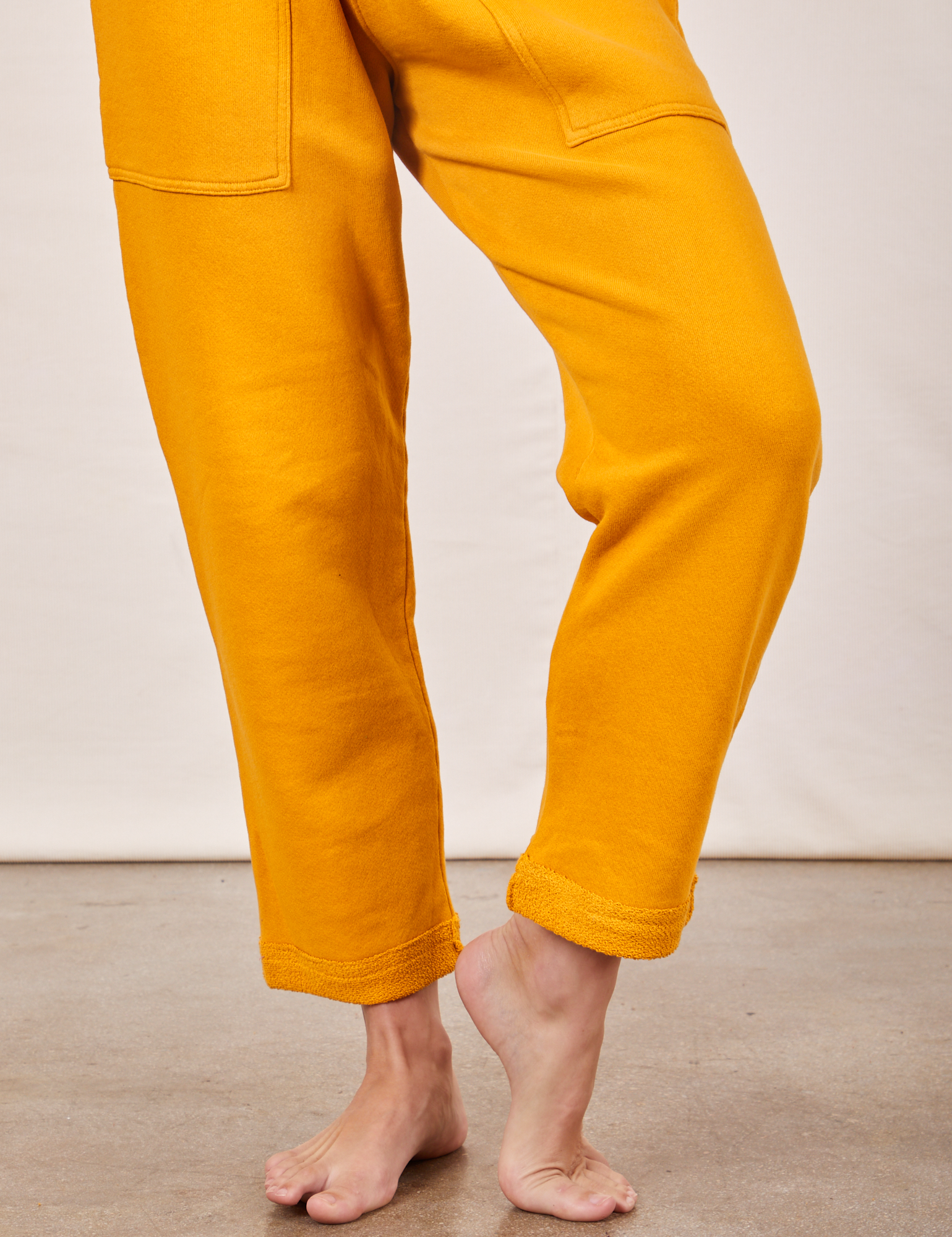 Cropped Rolled Cuff Sweatpants in Mustard Yellow pant leg close up on Alex