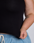 Close up of Juliet holding The Tank Top in Basic Black bottom hem