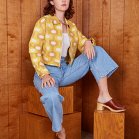 Alex is sitting on wooden boxes wearing Jacquard Ricky Jacket in Yellow
