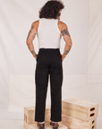 Back view of Denim Trouser Jeans in Black and vintage off-white Tank Top worn by Jesse