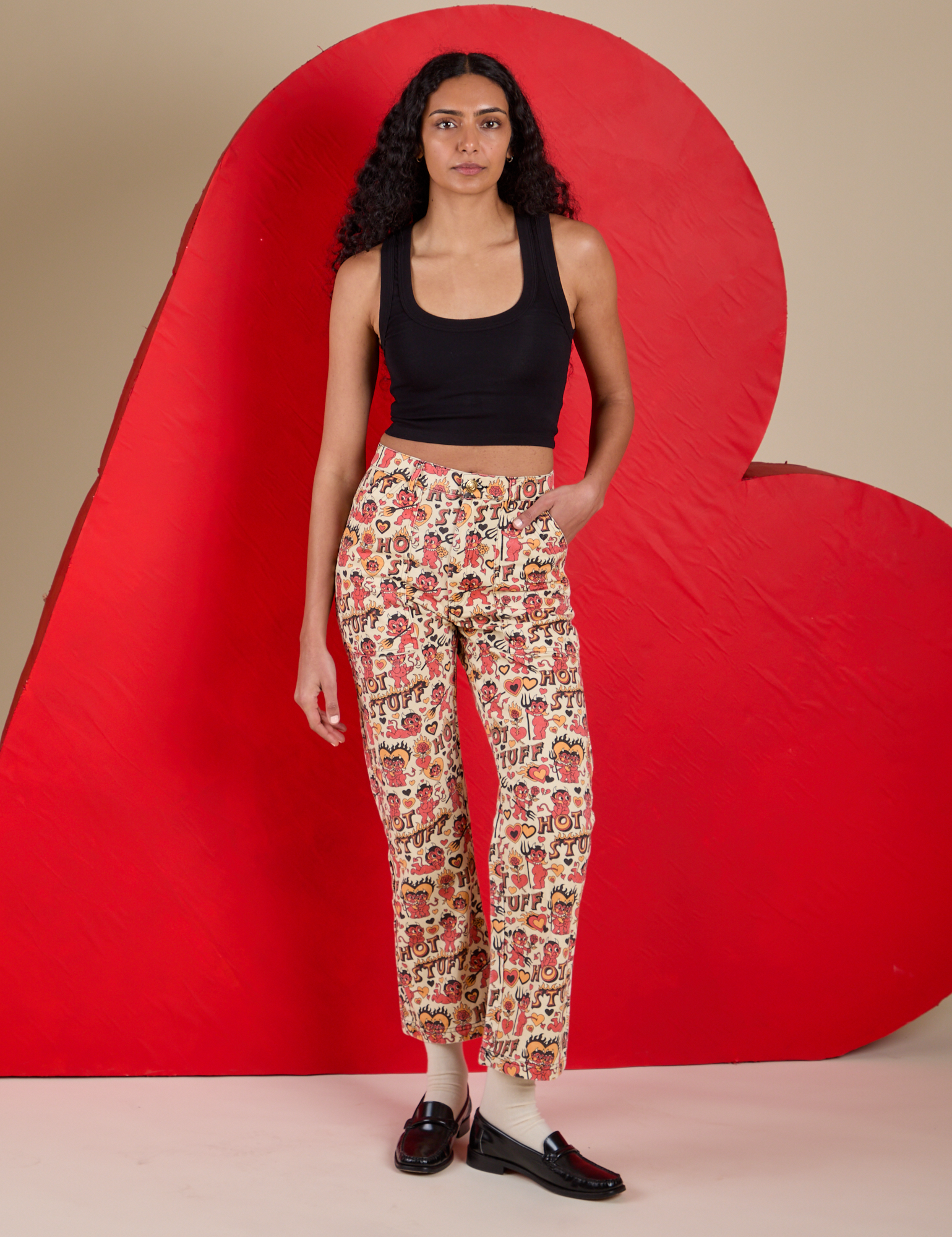 Shahana is 5’10 and wearing XS Work Pants in Hot Stuff Print paired with a black Cropped Tank