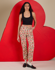 Shahana is 5’10 and wearing XS Work Pants in Hot Stuff Print paired with a black Cropped Tank