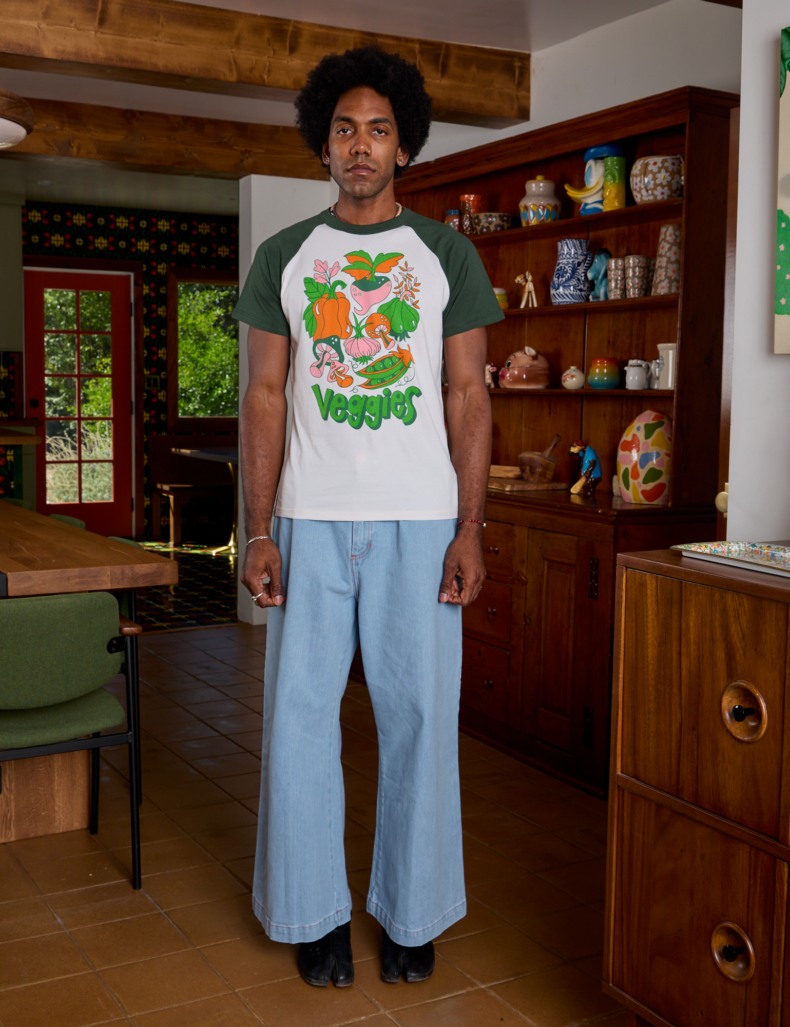 Jerrod is wearing Short Sleeve Raglan Tee in Veggies and light wash Indigo Wide Leg Trousers