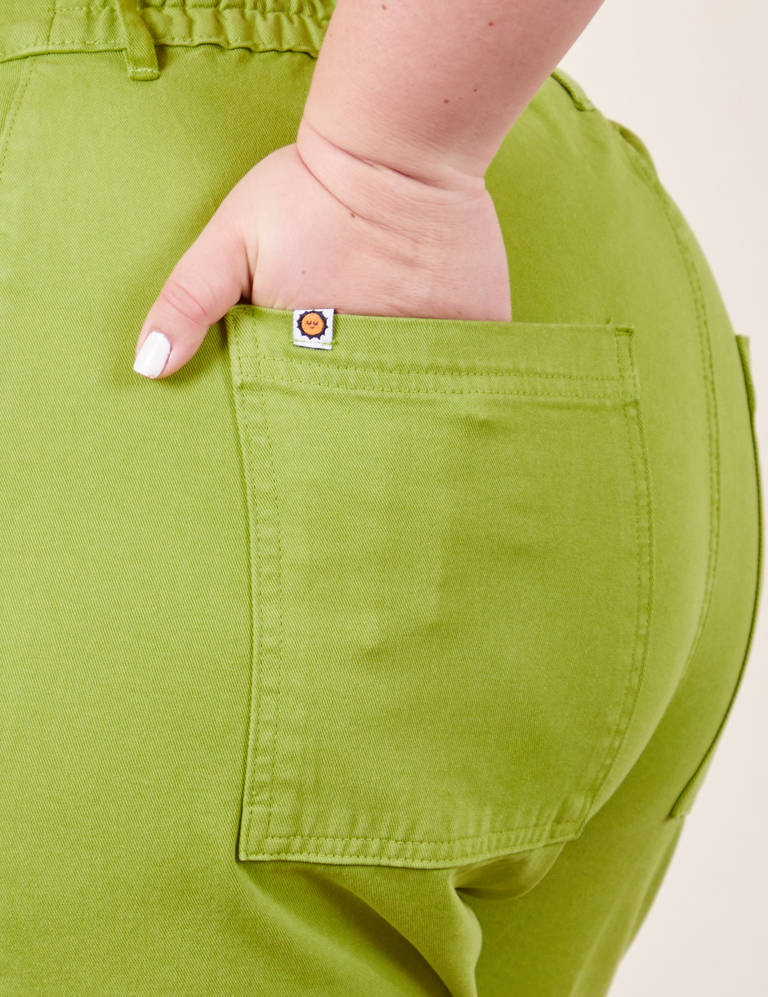 Back pocket close up of Western Pants in Gross Green. Worn by Ashley with her hand in the pocket.