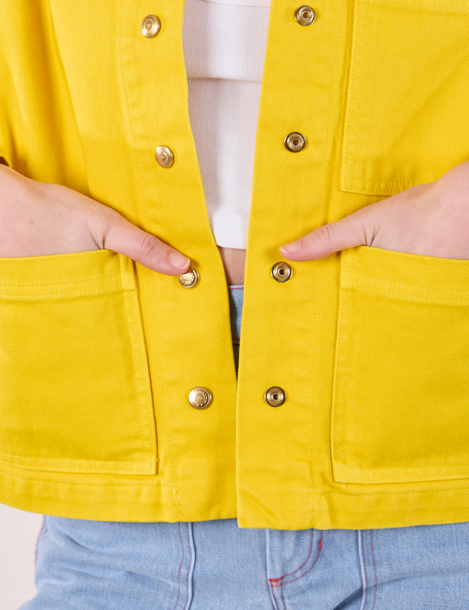 Close up of Alex&#39;s hands in both front pockets of Denim Work Jacket in Golden Yellow