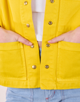 Close up of Alex's hands in both front pockets of Denim Work Jacket in Golden Yellow