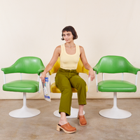 Soraya is sitting in a yellow chair wearing Work Pants in Olive Green and a butter yellow Tank Top