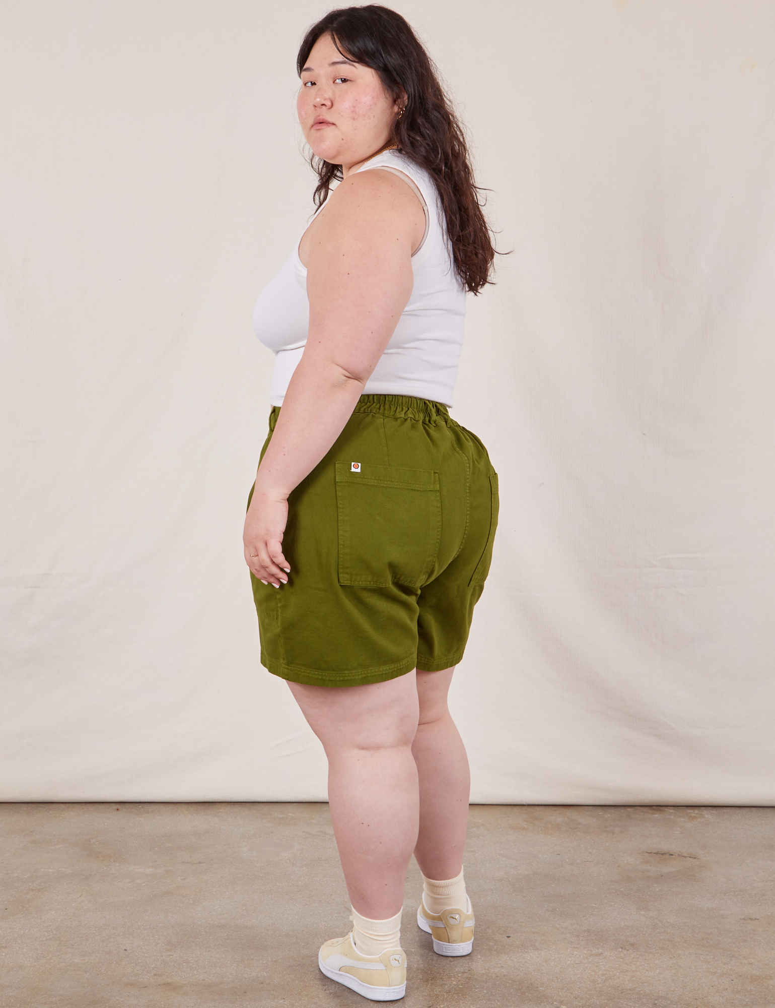 Angled back view of Classic Work Shorts in Summer Olive and Cropped Tank Top in vintage tee off-white on Ashley