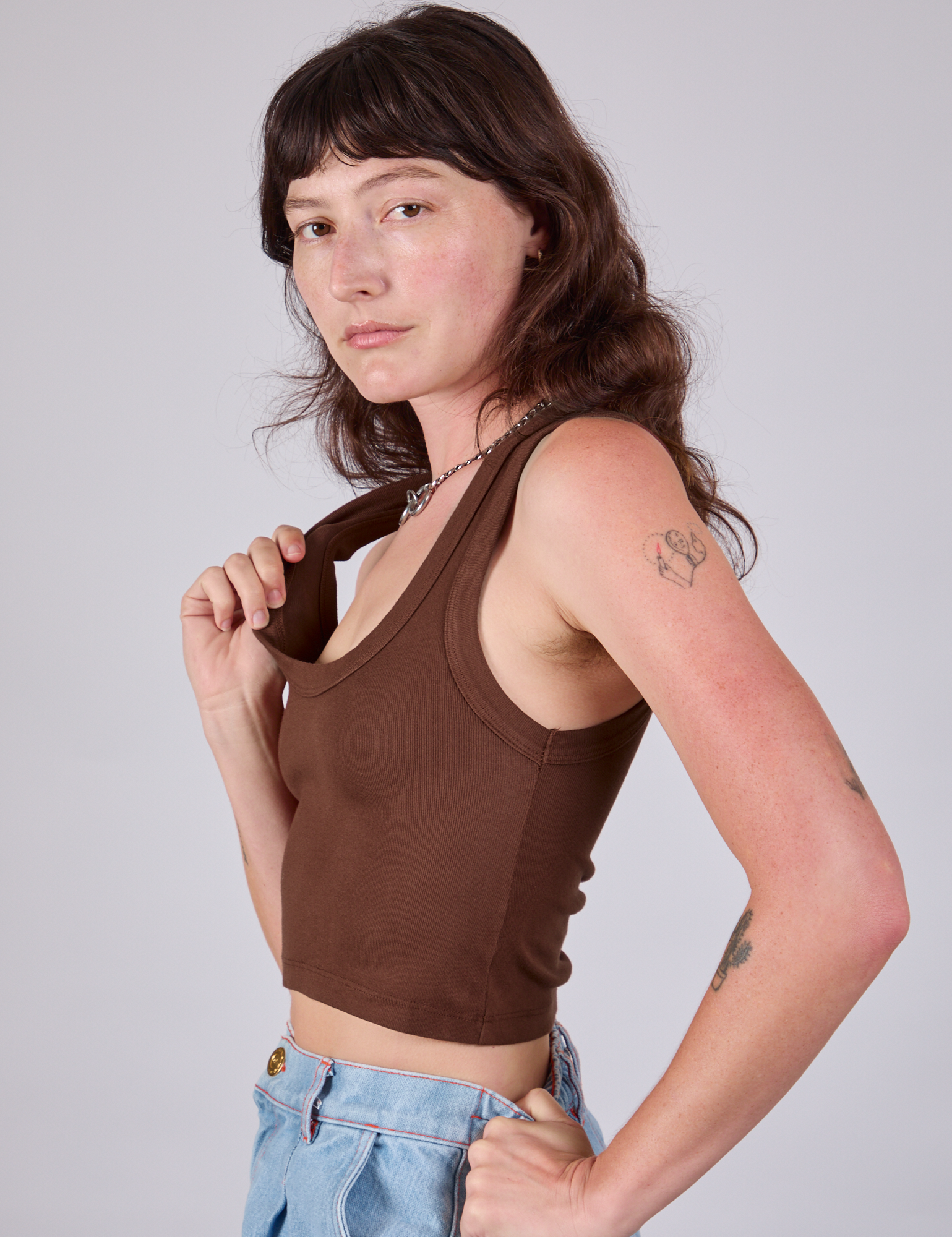 Cropped Tank Top in Fudgesicle Brown side view on Alex pulling on one of the straps