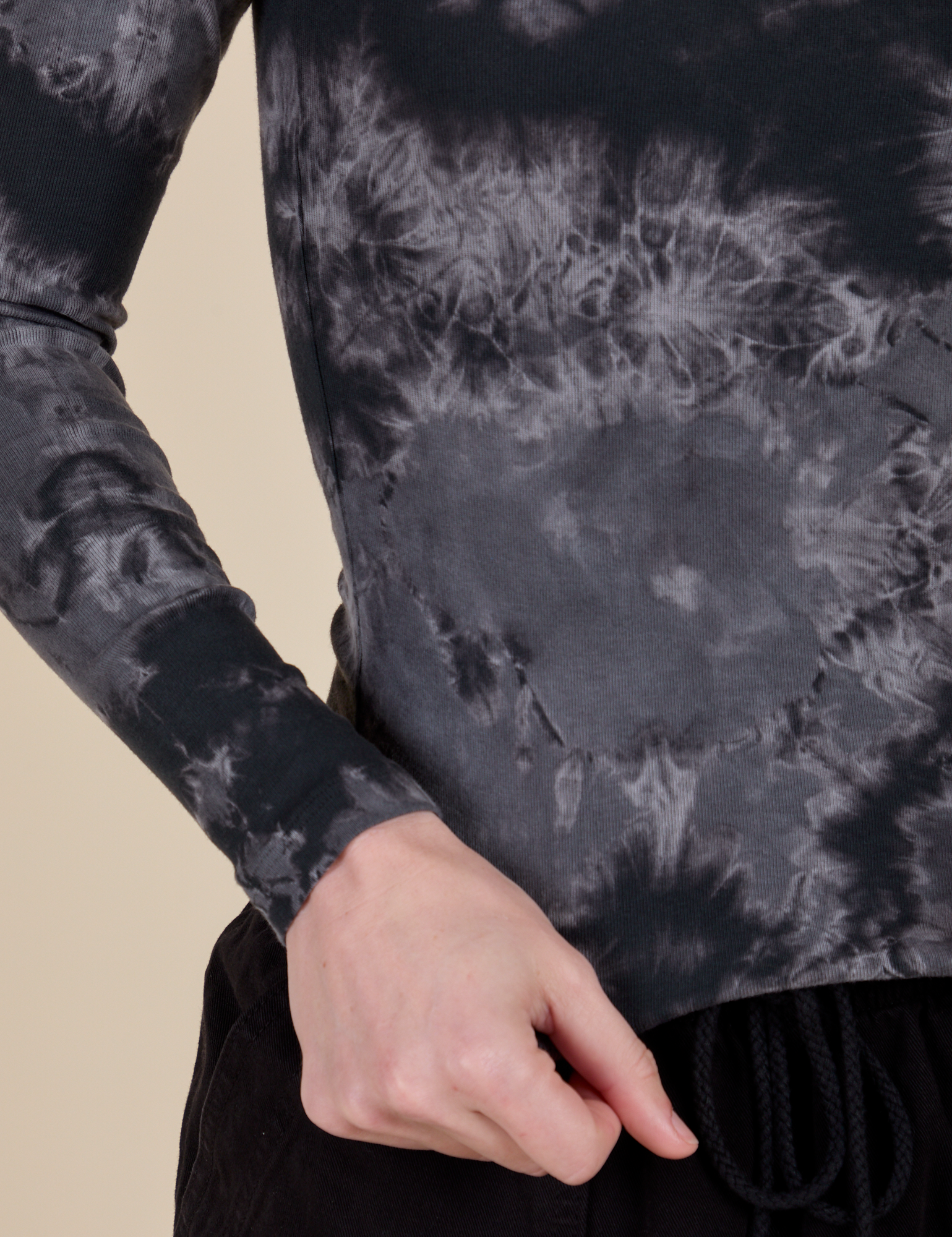 Long Sleeve Baby Tee in Black Magic Waters bottom close up with Alex holding the hem