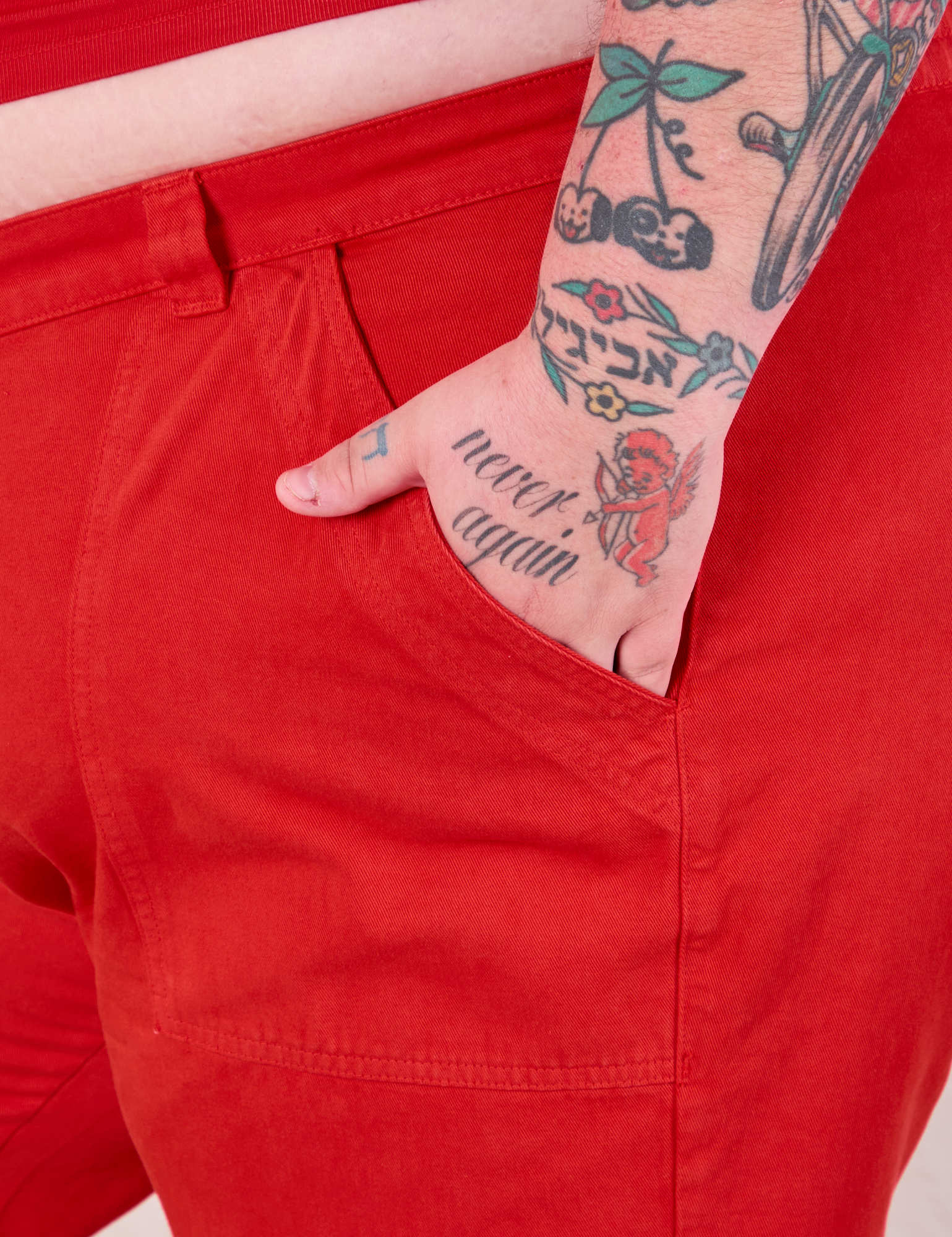 Close up of Sam&#39;s hand in the front pocket of Mid-Rise Work Pants in Mustang Red