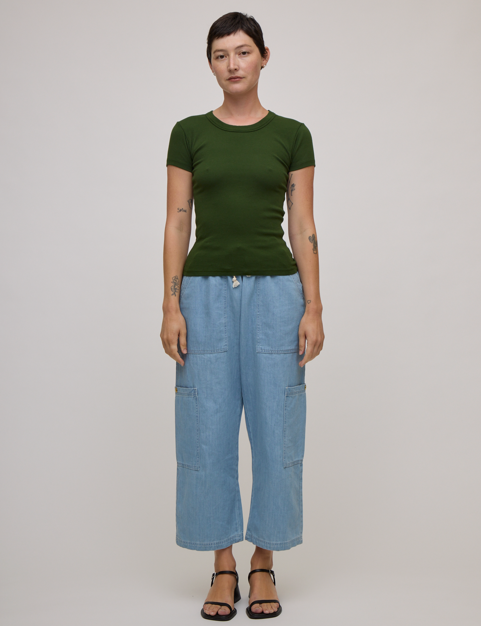Alex is wearing Baby Tee in Evergreen paired with light wash denim drop pocket pants