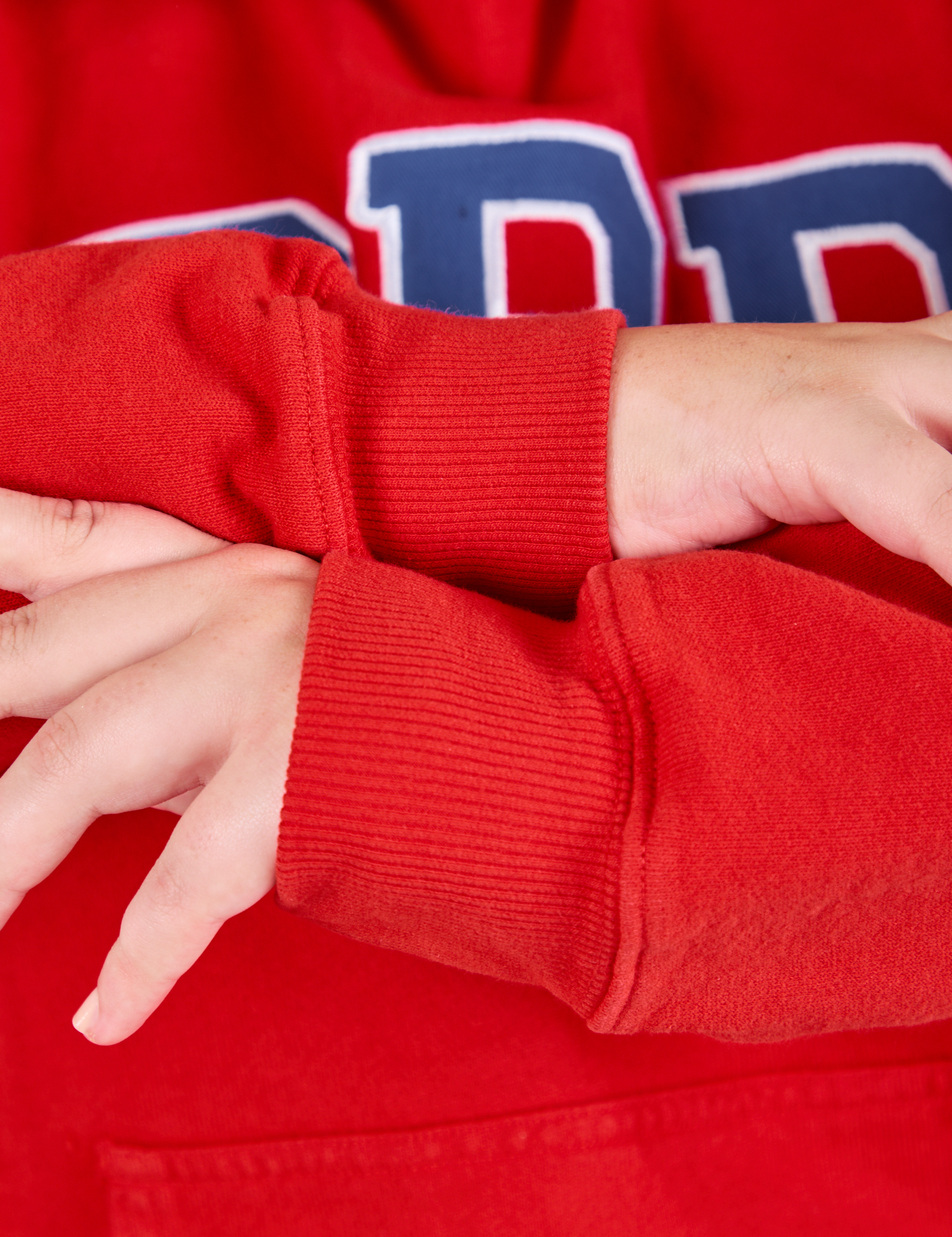 Collegiate Hoodie in Mustang Red sleeve cuff close up on Juliet