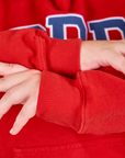 Collegiate Hoodie in Mustang Red sleeve cuff close up on Juliet