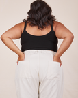 Back view of Cropped Cami in Basic Black and vintage off-white Western Pants worn by Alicia. She has both hands in the back pant pocket. 