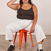 Alicia is sitting on an orange metal stool wearing Cropped Cami in Espresso Brown and vintage off-white Western Pants