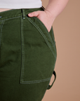 Close up of Ashley's hand in the front pocket of Carpenter Jeans in Evergreen