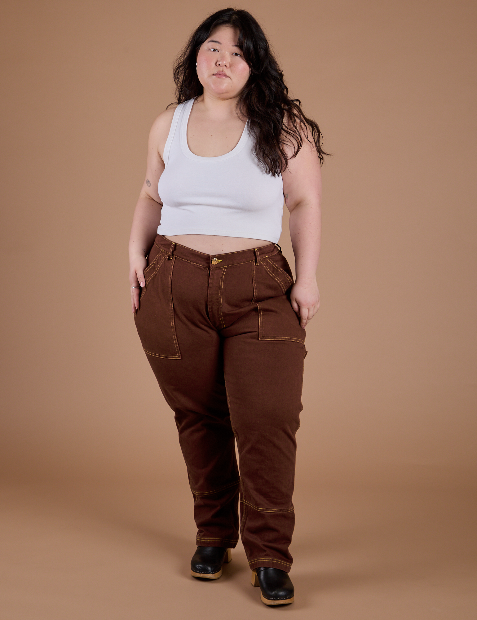 Ashley is 5’7” and wearing 1XL Carpenter Jeans in Fudgesicle Brown paired with a Cropped Tank in Vintage Tee White