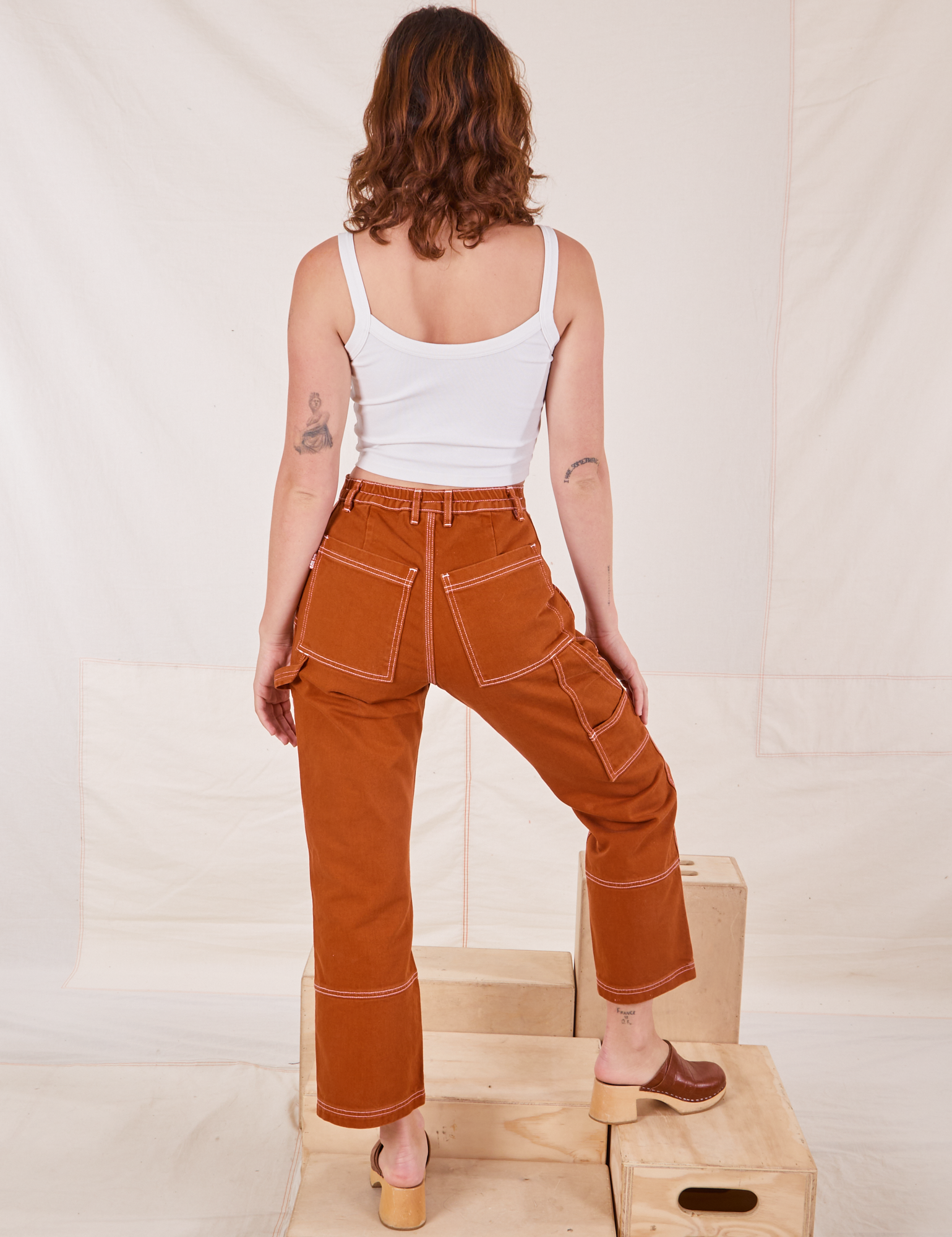Back view of Carpenter Jeans in Burnt Terracotta and vintage off-white Cropped Cami on Alex
