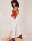 Side view of Carpenter Jeans in Vintage Off-White and burnt terracotta Cropped Tank Top on Jesse